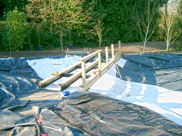preparing the pond liner and bridge for swimming pond